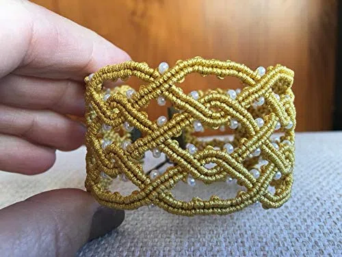 Pulsera macrame celta hecha a mano con hilo dorado.Mide aprox.19 cm. de largo y 3,5 cm.de ancho .Cierre y adorno colgalte.