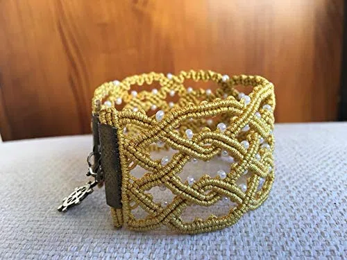 Pulsera macrame celta hecha a mano con hilo dorado.Mide aprox.19 cm. de largo y 3,5 cm.de ancho .Cierre y adorno colgalte.